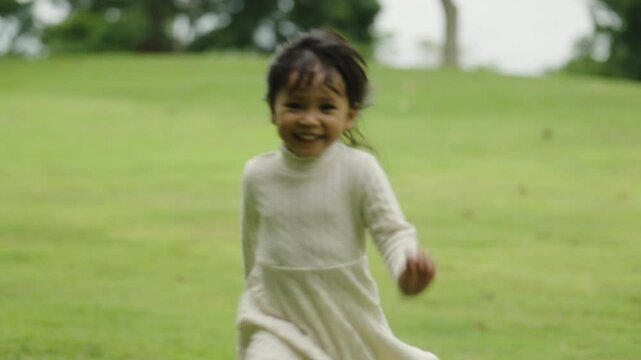 happy toddle girl in white dress running on green grass field