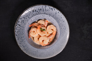Shrimp in a creamy garlic sauce with parsley and lime in blue bowl. Top view