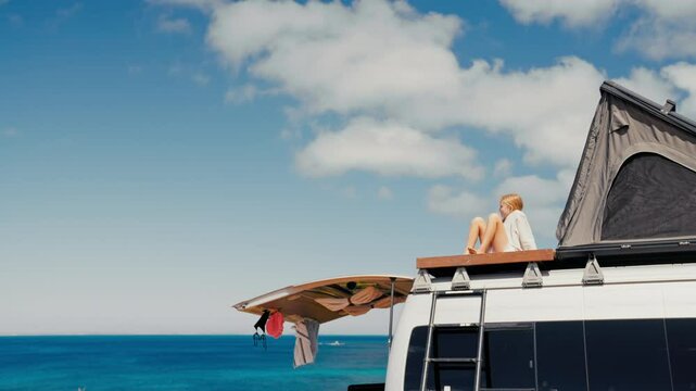 Little girl enjoys the view of the ocean from the rooftop of a camper van