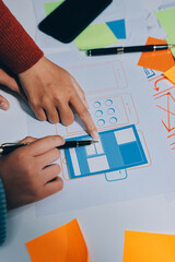 UX UI designer testing prototype on a phone, discussing and brainstorming on wireframes for a...
