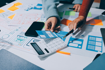 UX UI designer testing prototype on a phone, discussing and brainstorming on wireframes for a...