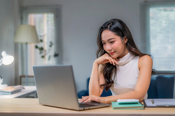 woman is sitting at a desk with a laptop in front of her