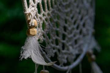 Dreamcatcher with White Feathers Swaying Outdoors Against Blue Sky and Green Trees