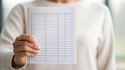 Person holds blank notebook with lined pages, symbolizing organization and planning. This preventive measure can aid in cancer screening awareness