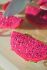 Slicing vibrant dragon fruit on a wooden board