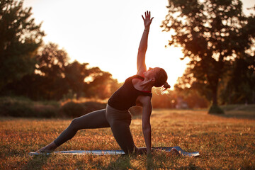 Woman practicing yoga and stretching in the park on a hot sunny summertime day.