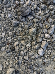 Close up of mixed gravel and natural pebbles in various sizes and tones, creating a raw, rough texture ideal for use in backgrounds, construction themes, or organic surface designs
