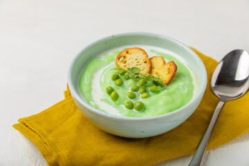 Green pea soup on a wooden table. Fresh pea soup bowl. Delicious healthy cream soup in a bowl with green peas and croutons. Healthy vegan puree. Copy space. Space for text.