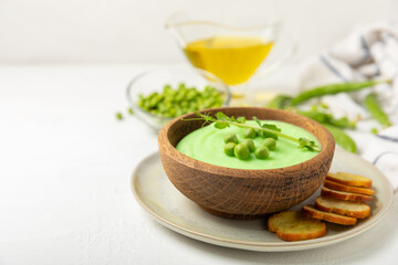 Green pea soup on a wooden table. Fresh pea soup bowl. Delicious healthy cream soup in a bowl with green peas and croutons. Healthy vegan puree. Copy space. Space for text.