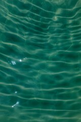 Blue water with ripples on the surface. Defocus blurred transparent blue colored clear calm water surface texture with splashes and bubbles. Water waves with shining pattern texture background.