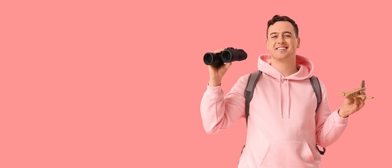 Young man with binoculars and wooden airplane on pink background with space for text