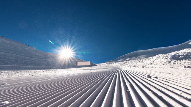 Ready ski piste after snowcat and snow grooming with velvet texture with nobody on it at sunny day