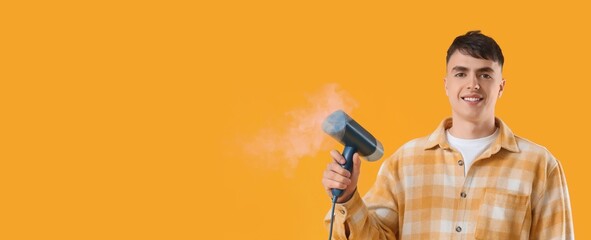 Young man with steamer for clothes on yellow background with space for text