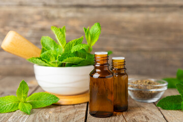 Essential oil mint on a wooden background. Peppermint essential oil with fresh mint leaves. A...