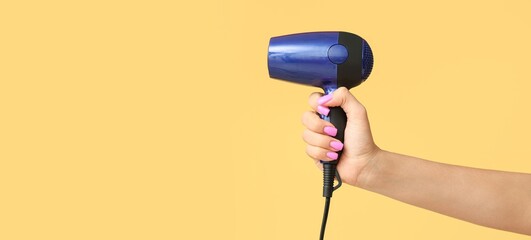 Hand with hair dryer on yellow background with space for text