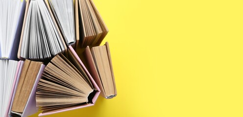 Many books on yellow background with space for text, top view