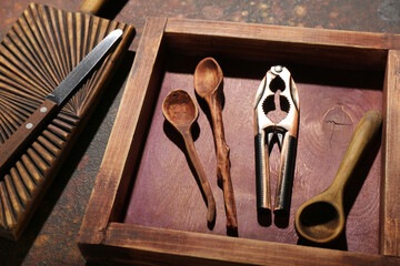 Wooden tray with nutcracker and spoons on grunge background