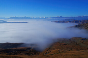 Aerial view of mountains covered in fog under a clear blue sky on a sunny day landscape scene