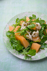 Plate of melon and arugula salad. Fresh, light summer dish with vibrant colors and healthy ingredients