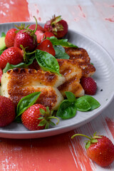 Plate of summer salad with fresh strawberries, arugula, and grilled halloumi cheese. Bright, flavorful, and healthy dish perfect for warm seasons.