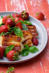 Plate of summer salad with fresh strawberries, arugula, and grilled halloumi cheese. Bright, flavorful, and healthy dish perfect for warm seasons.