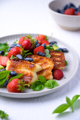 Plate of summer salad with fresh strawberries, arugula, and grilled halloumi cheese. Bright, flavorful, and healthy dish perfect for warm seasons.