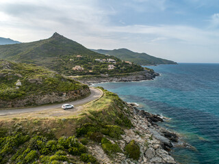 Aerial view car Roadtrip Winding road along rocky coast of Cap Corse peninsula on Corsica island...