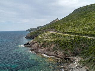 Aerial view car Roadtrip Winding road along rocky coast of Cap Corse peninsula on Corsica island...