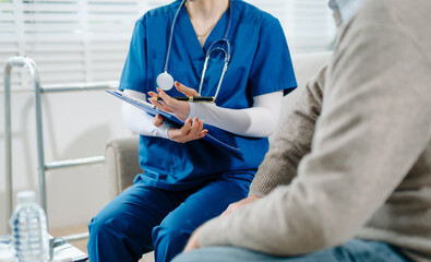 Senior man with chest pain speaks to nurse noting symptoms on tablet at home. Healthcare, heart...