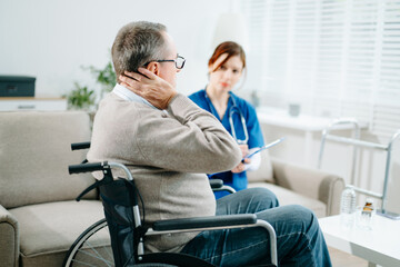 A caring nurse in blue scrubs conducts a neck pain consultation with a senior wheelchair patient at...