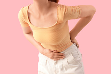 Young woman suffering from stomach ache on pink background, closeup