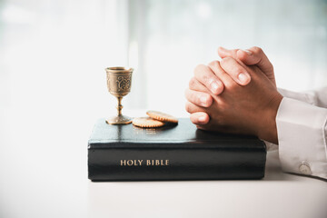 During the holy communion ceremony in church, a hand is extended in faith to receive the sacred...