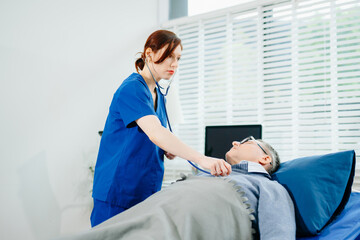 Fototapeta premium A nurse in blue scrubs conducts a bedside checkup for a senior patient in a bright room, highlighting real people,