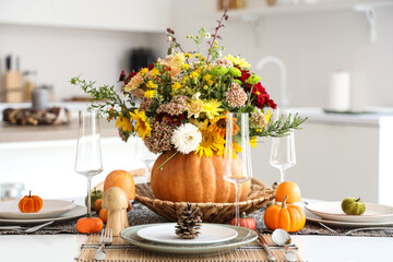 Pumpkin with autumn bouquet on dining table in kitchen, closeup