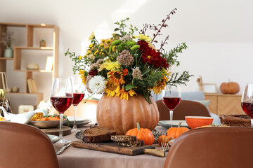 Pumpkin with autumn bouquet on festive dining table in room, closeup