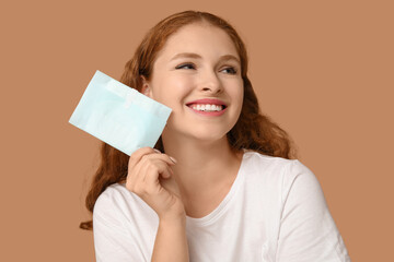 Beautiful young woman with menstrual pad on brown background