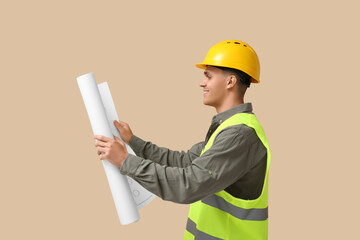 Young male engineer with blueprint on beige background