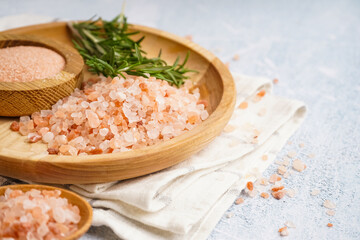 Wooden plate and bowl of Himalayan pink salt with rosemary on white background