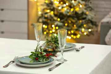 Beautiful table setting with mistletoe for Christmas dinner in living room