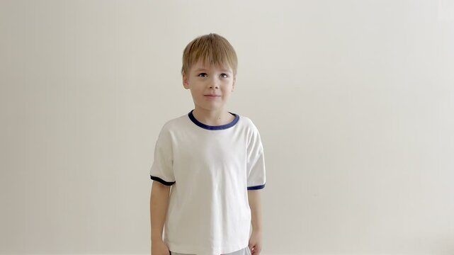 A young Caucasian boy in a light-colored t-shirt throws a small tantrum, showing signs of frustration and demanding something with an upset expression. His body language includes pouting lips