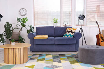 Interior of stylish living room with sofa, table and pouf