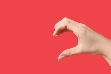 Female hand showing half heart gesture on red background. Valentine's Day celebration