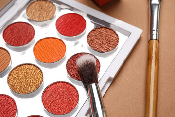 Set of eyeshadows with brushes on beige background. Closeup