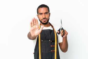 Young Ecuadorian design man holding scissors isolated on white background making stop gesture