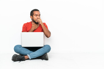Young Ecuadorian man with a laptop sitting on the floor isolated on white background is suffering...