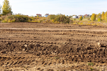 Empty land plot with tire prints prepared for new housing in rural area. Clearing and leveling of...