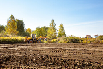Yellow bulldozer at a construction site. Big wheel excavator leveling and clearing the land plot...