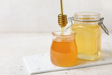 Jars of sweet honey with dipper on white grunge table