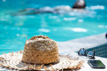 Close up of a straw hat and other objects of a local Costa Rican man taking a dip in the pool in...