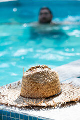 Close up of a straw hat and a blurred local Costa Rican man taking a dip in the pool in Tortuguero, Costa Rica